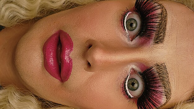 Drag Queen mit dramatischem Make-up, langen Wimpern und überraschtem Gesichtsausdruck