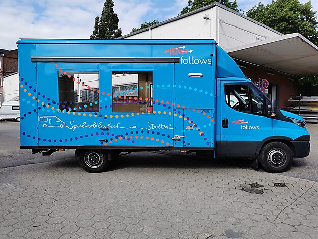 Blauer Truck mit Bedienungsfenstern auf der Seite, geparkt auf einem Platz